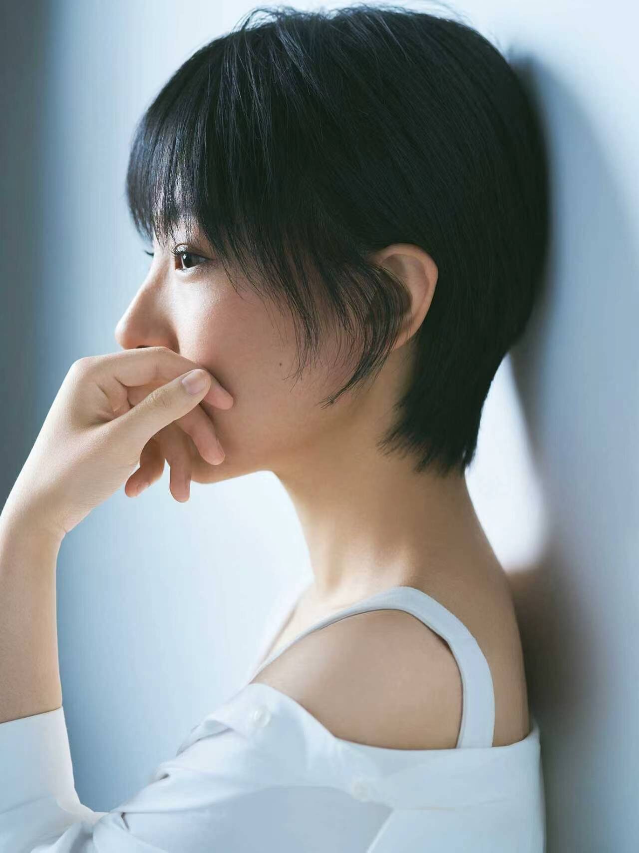 Profile against a pale wall, hand at the chin